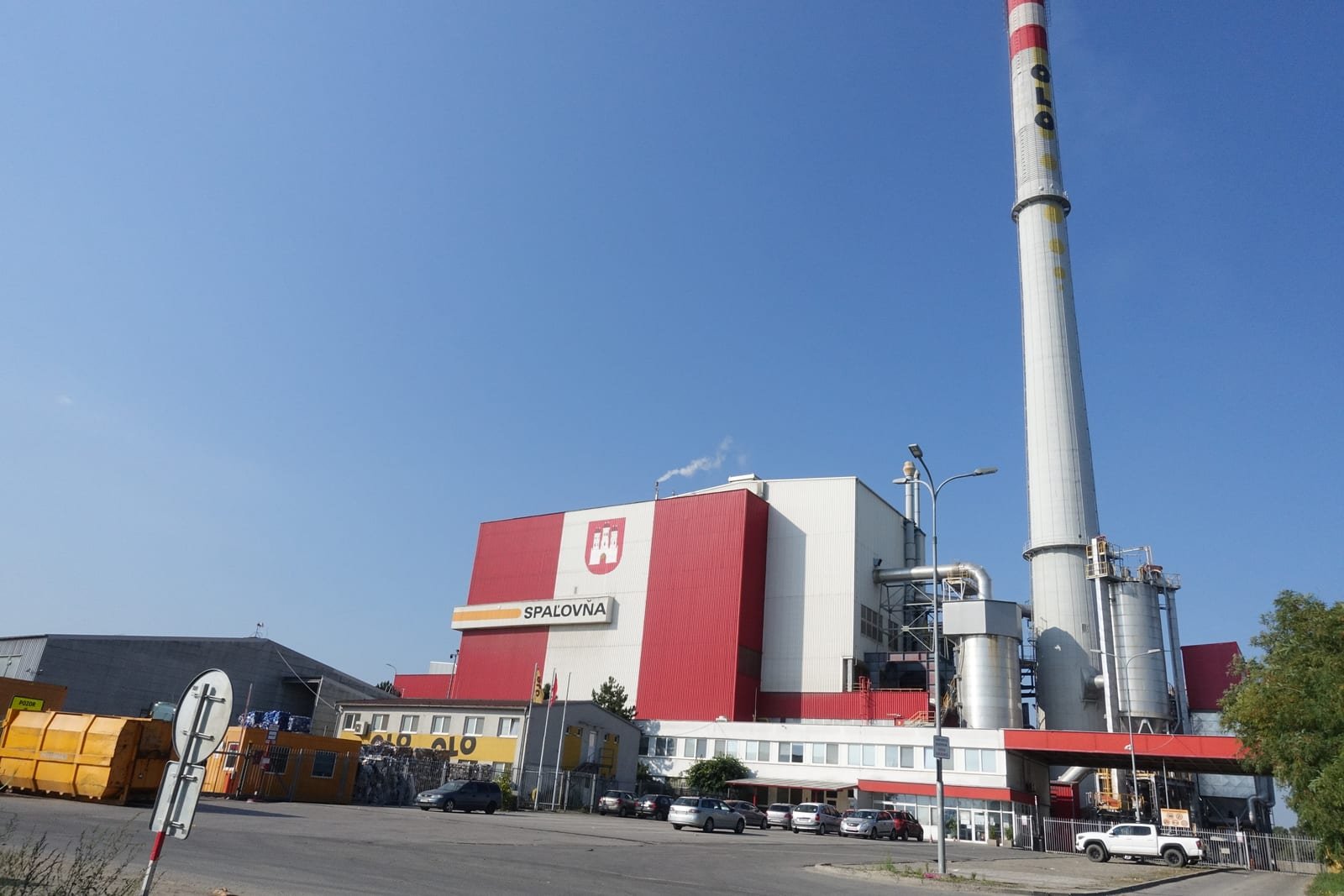 Illustrative image: a red-and-white waste incineration plant with a tall chimney under a blue sky.