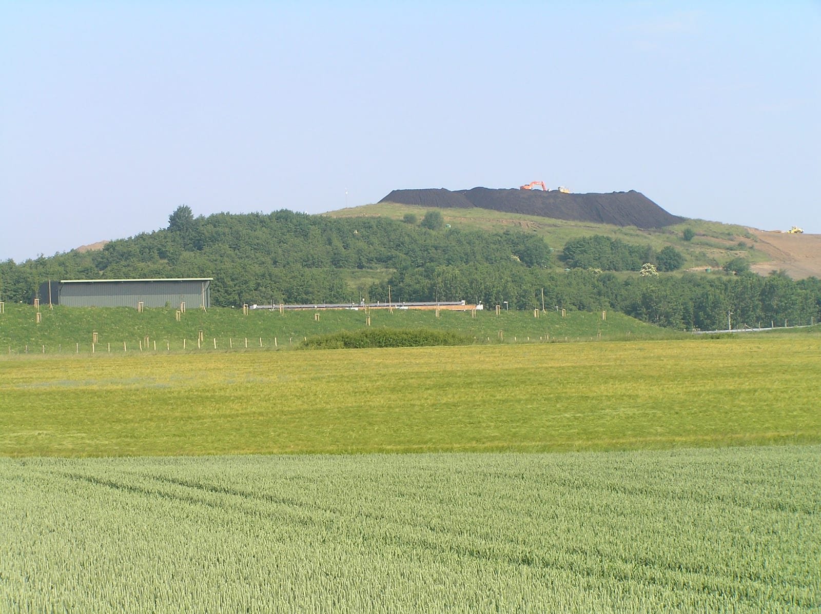 Illustrative image: a landfill mound behind fields in Germany.